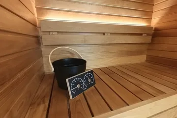 Auroom Cala Glass, just inside the door: The horizontal wood walls, the two bench levels and the bucket and thermometer on the upper bench.
