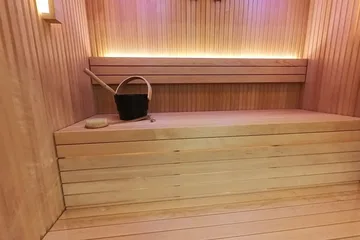 Auroom Libera Glass, just inside the door: The HUUM heater in its wooden rail on the left, the benches and the lit backrest ahead.