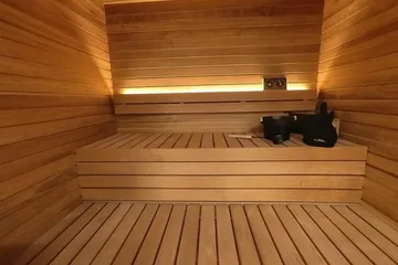 Auroom Mira L, just inside the door: Door open: the heater on the left, the straight benches ahead, the showroom behind.