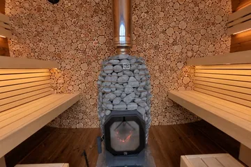 Leil Round Cube Single, round Cube Single: Look toward the juniper wall and wood-burning heater, then turn around to explore the opposing benches and glass front. Choose the front and side views to step outside this same sauna.