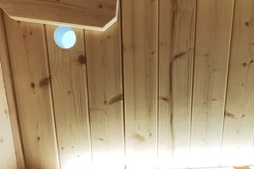 SaunaLife X6, upper bench: A higher viewpoint across the illuminated backrest and wood-lined ceiling.